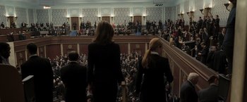 Movie still from “Eagle Eye” (2008), directed by D.J. Caruso – Two women in black suits walking up a flight of stairs in front of an audience; Wide shot, High angle