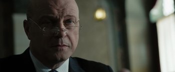 Movie still from “Eagle Eye” (2008), directed by D.J. Caruso – An older man wearing glasses and a suit; Close Up shot, Over the shoulder angle