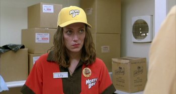 Movie still from “Eagle vs Shark” (2007), directed by Taika Waititi – A woman wearing a meaty boy hat standing next to boxes; Close Up shot, Low angle
