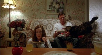 Movie still from “Eagle vs Shark” (2007), directed by Taika Waititi – A woman and a man sitting on a couch with a cat; Medium shot, Overhead angle