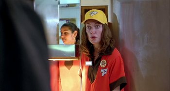 Movie still from “Eagle vs Shark” (2007), directed by Taika Waititi – A woman in a yellow hat is standing in front of a mirror; Close Up shot, Over the shoulder angle