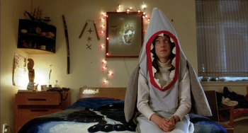 Movie still from “Eagle vs Shark” (2007), directed by Taika Waititi – A person sitting on a bed wearing a shark costume; Medium shot, High angle
