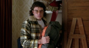 Movie still from “Eagle vs Shark” (2007), directed by Taika Waititi – A man holding an umbrella in a room; Medium shot, High angle