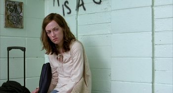 Movie still from “Eagle vs Shark” (2007), directed by Taika Waititi – A woman sitting against a wall with a bag in front of her face; Medium shot, Low angle