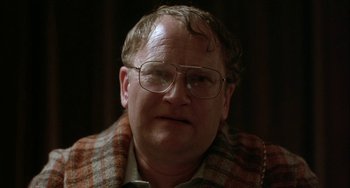 Movie still from “Eagle vs Shark” (2007), directed by Taika Waititi – An older man wearing glasses and a plaid jacket; Close Up shot, Over the shoulder angle