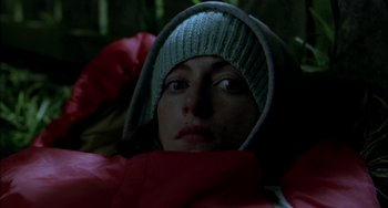 Movie still from “Eagle vs Shark” (2007), directed by Taika Waititi – A woman wearing a green hat is laying in a sleeping bag in the dark; Close Up shot, Overhead angle
