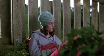 Movie still from “Eagle vs Shark” (2007), directed by Taika Waititi – A woman sitting on the ground wearing a green hat; Medium shot, Low angle