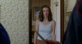 Movie still from “Eagle vs Shark” (2007), directed by Taika Waititi – A woman standing in a room holding a knife in her hand; Medium shot, Over the shoulder angle