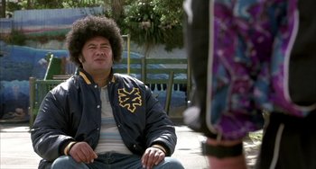 Movie still from “Eagle vs Shark” (2007), directed by Taika Waititi – A man sitting on the ground wearing a jacket; Close Up shot, Over the shoulder angle