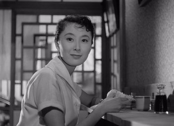A woman sitting at a table with a cup in her hand