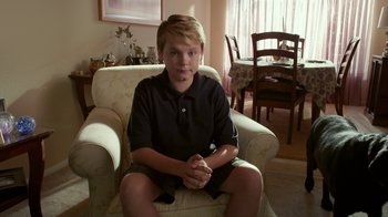 Movie still from “Earth to Echo” (2014), directed by Dave Green – A boy sitting in a chair in a living room; Medium shot, High angle
