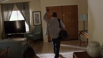Movie still from “Earth to Echo” (2014), directed by Dave Green – A man walking in a living room holding a bag of luggage; Wide shot, High angle