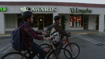 Movie still from “Earth to Echo” (2014), directed by Dave Green – Two men riding bikes down a street in front of a store; Wide shot, Low angle