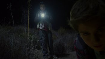 Movie still from “Earth to Echo” (2014), directed by Dave Green – A man holding a flashlight while standing in a field; Medium shot, Over the shoulder angle