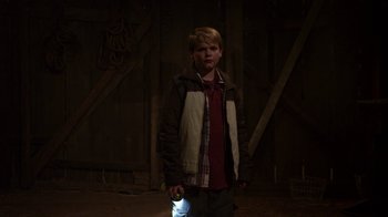 Movie still from “Earth to Echo” (2014), directed by Dave Green – A young boy holding a flashlight in a dark room; Medium shot, Over the shoulder angle