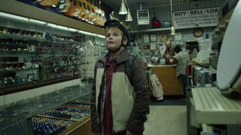 Movie still from “Earth to Echo” (2014), directed by Dave Green – A young boy wearing a helmet in a store; Medium shot, Over the shoulder angle