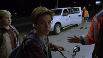 Movie still from “Earth to Echo” (2014), directed by Dave Green – A young man riding a bike down a street at night; Medium shot, Over the shoulder angle