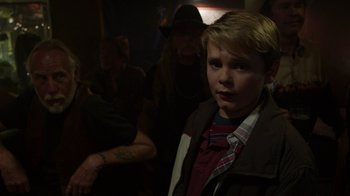 Movie still from “Earth to Echo” (2014), directed by Dave Green – A young boy standing next to a group of people in a dark room; Close Up shot, Over the shoulder angle