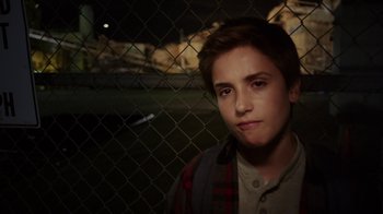 Movie still from “Earth to Echo” (2014), directed by Dave Green – A young man standing next to a chain link fence at night; Close Up shot, High angle
