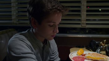 Movie still from “Earth to Echo” (2014), directed by Dave Green – A young man sitting at a table with a plate of food; Close Up shot, High angle