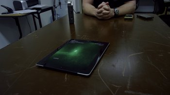 Movie still from “Earth to Echo” (2014), directed by Dave Green – A man sitting at a wooden table with a tablet; Medium shot, Overhead angle