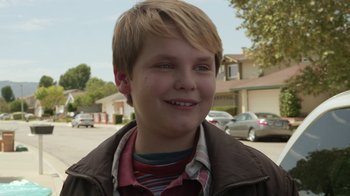 Movie still from “Earth to Echo” (2014), directed by Dave Green – A young boy smiling for the camera on the street; Close Up shot, Over the shoulder angle