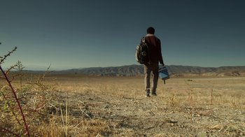 Movie still from “Earth to Echo” (2014), directed by Dave Green – A man walking across a dry grass field; Wide shot, Low angle