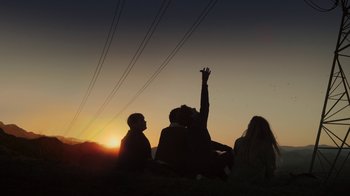 Movie still from “Earth to Echo” (2014), directed by Dave Green – A group of people sitting on top of a grass covered field; Wide shot, Low angle