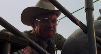 Movie still from “Eat My Dust” (1976), directed by Charles B. Griffith – An older man wearing a cowboy hat and glasses; Close Up shot, Low angle