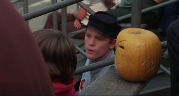 Movie still from “Eat My Dust” (1976), directed by Charles B. Griffith – A young man sitting in front of a pumpkin; Close Up shot, Over the shoulder angle