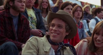 Movie still from “Eat My Dust” (1976), directed by Charles B. Griffith – A man with a cowboy hat and a scarf around his neck; Close Up shot, Over the shoulder angle