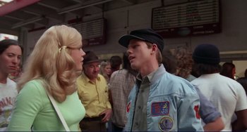 Movie still from “Eat My Dust” (1976), directed by Charles B. Griffith – A man and a woman are talking to each other in a crowd; Medium shot, Over the shoulder angle