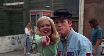 Movie still from “Eat My Dust” (1976), directed by Charles B. Griffith – A man and a woman standing next to each other; Medium shot, Low angle