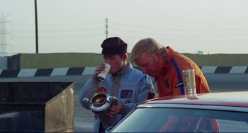Movie still from “Eat My Dust” (1976), directed by Charles B. Griffith – Two men are standing next to each other; Medium shot, Low angle