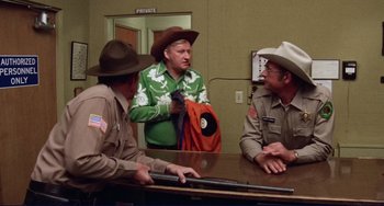 Movie still from “Eat My Dust” (1976), directed by Charles B. Griffith – A group of men sitting around a table; Medium shot, Over the shoulder angle
