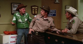 Movie still from “Eat My Dust” (1976), directed by Charles B. Griffith – A man in a sheriff's outfit and a woman in a sheriff's outfit; Medium shot, Over the shoulder angle