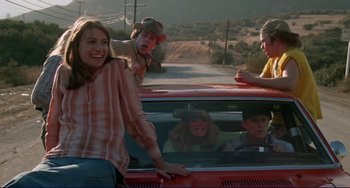 Movie still from “Eat My Dust” (1976), directed by Charles B. Griffith – A group of people sitting in the back of a red car; Medium shot, Low angle