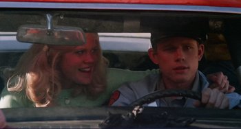 Movie still from “Eat My Dust” (1976), directed by Charles B. Griffith – A man and a woman sitting in the drivers seat of a car; Close Up shot, Low angle