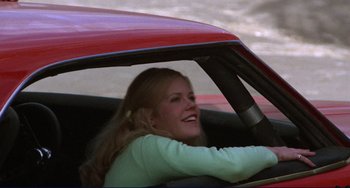 Movie still from “Eat My Dust” (1976), directed by Charles B. Griffith – A woman sitting in the driver's seat of a red car; Medium shot, Low angle