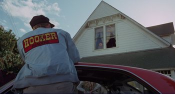 Movie still from “Eat My Dust” (1976), directed by Charles B. Griffith – A man standing in front of a red car; Medium shot, Low angle