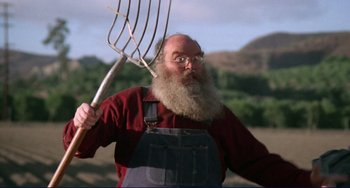 Movie still from “Eat My Dust” (1976), directed by Charles B. Griffith – An old man with a long beard holding a fork in a field; Medium shot, Low angle