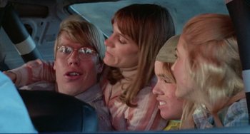 Movie still from “Eat My Dust” (1976), directed by Charles B. Griffith – A group of people in the back of a car; Medium shot, Over the shoulder angle