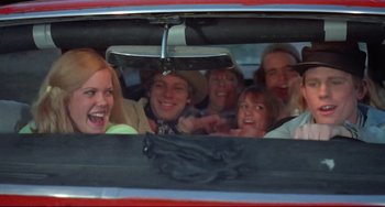 Movie still from “Eat My Dust” (1976), directed by Charles B. Griffith – A group of people in the back of a red car; Medium shot, Low angle