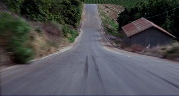 Movie still from “Eat My Dust” (1976), directed by Charles B. Griffith – A view of a road from a car window looking straight ahead; Extreme Wide shot, High angle