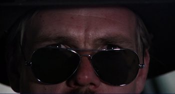 Movie still from “Eat My Dust” (1976), directed by Charles B. Griffith – A person wearing sunglasses; Extreme Close Up shot, Low angle