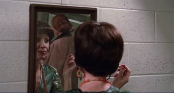 Movie still from “Eat My Dust” (1976), directed by Charles B. Griffith – A woman looking in the mirror while holding a pair of earrings; Close Up shot, Over the shoulder angle