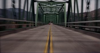 Movie still from “Eat My Dust” (1976), directed by Charles B. Griffith – A car is driving on a bridge over a river; Extreme Wide shot, High angle