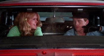 Movie still from “Eat My Dust” (1976), directed by Charles B. Griffith – A man and a woman sitting in the back of a red car; Close Up shot, Over the shoulder angle
