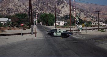 Movie still from “Eat My Dust” (1976), directed by Charles B. Griffith – A police car is parked on the side of the road; Extreme Wide shot, High angle