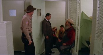 Movie still from “Eat My Dust” (1976), directed by Charles B. Griffith – A group of men sitting in front of each other in a jail cell; Wide shot, High angle